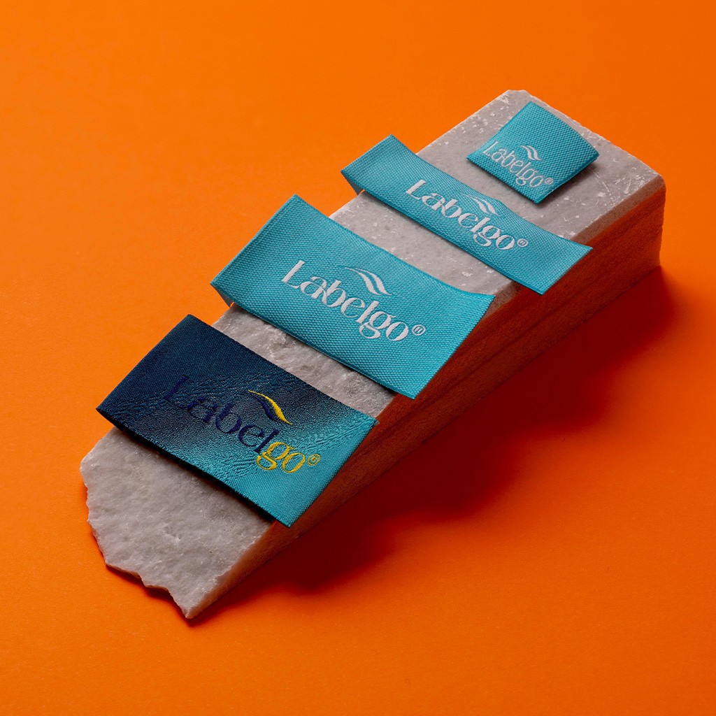 Turquoise woven labels with gold print on dark red surface.
